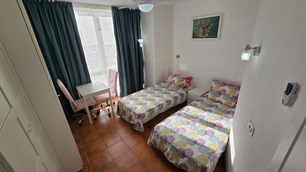 een kamer met twee bedden, een bureau en een raam bij Tenerife flyport in San Isidro