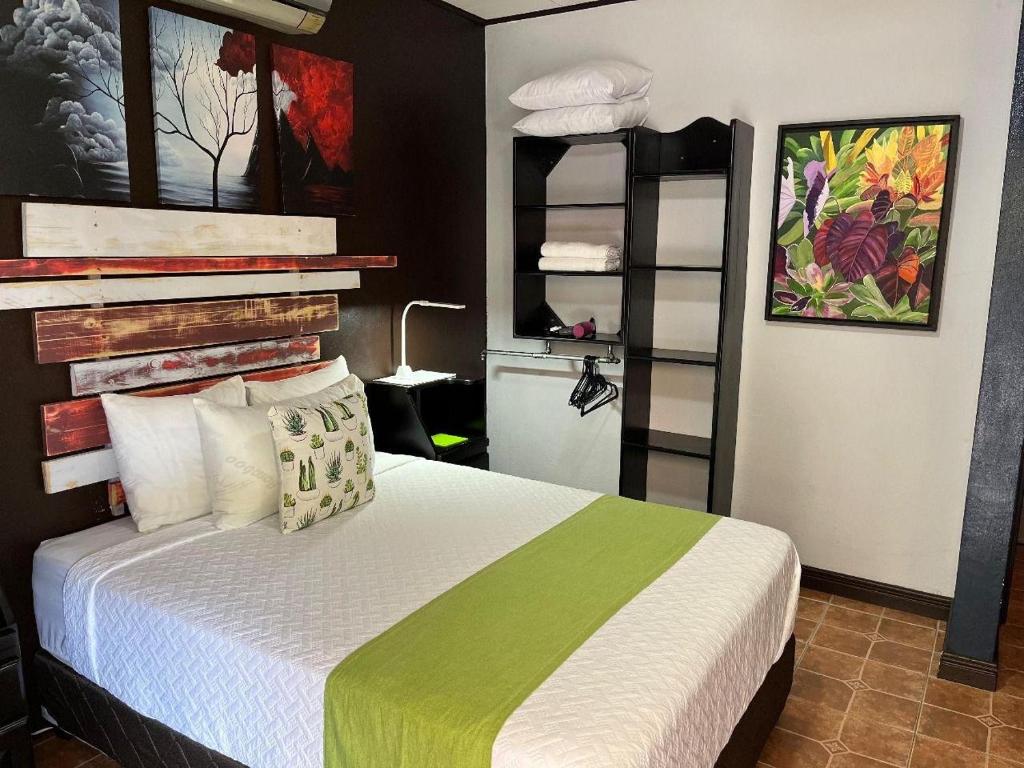 1 dormitorio con 1 cama con manta verde y blanca en Casa Olas, en Quepos