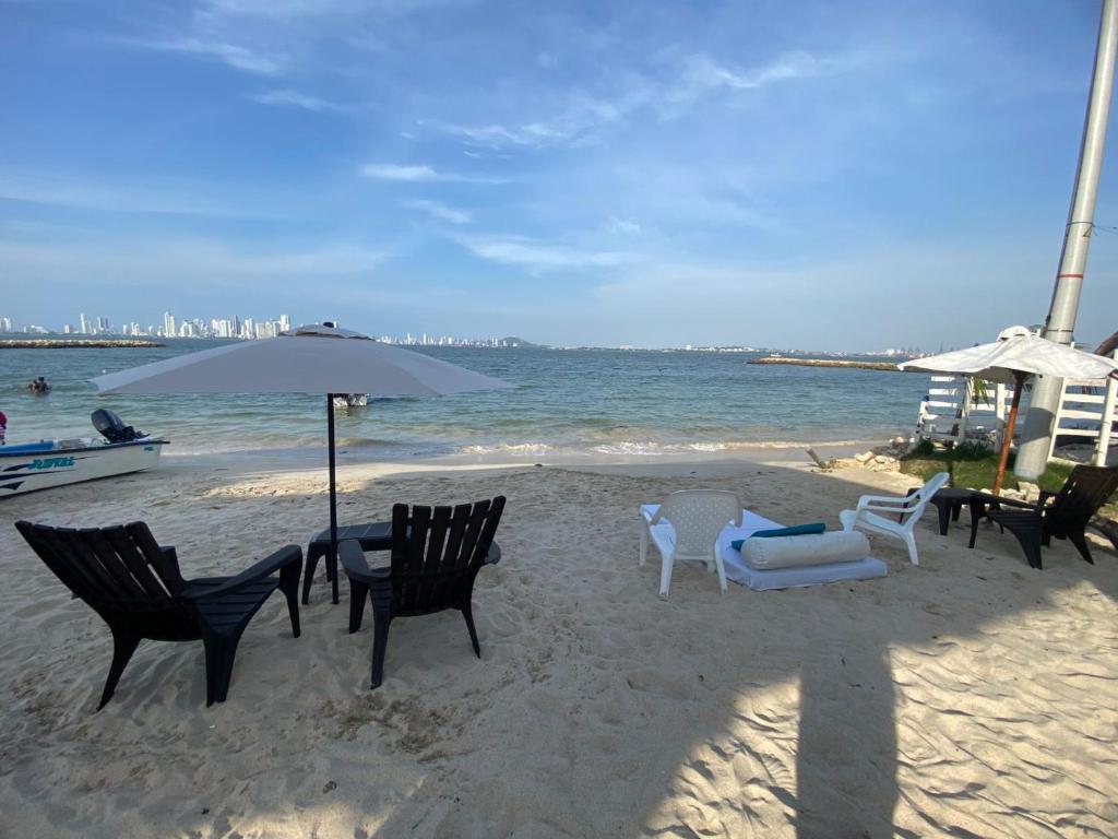 Orilla beach house في Playa Punta Arena: مجموعة من الكراسي ومظلة على الشاطئ