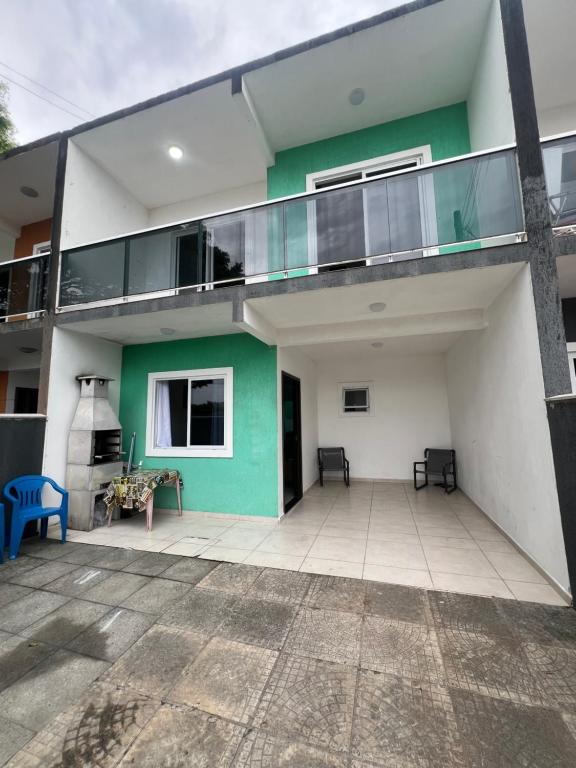 ein grün-weißes Haus mit Balkon in der Unterkunft Residencial Passos 2 in Guaratuba