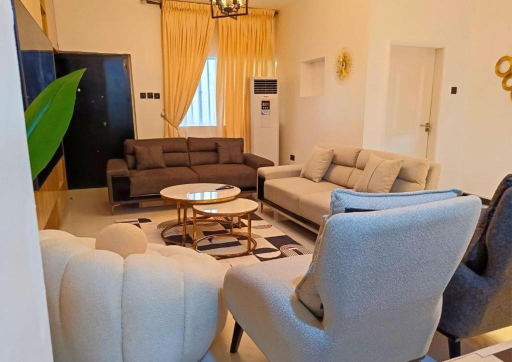 un soggiorno con un divano, sedie e un tavolo di Signature Apartments a Warri