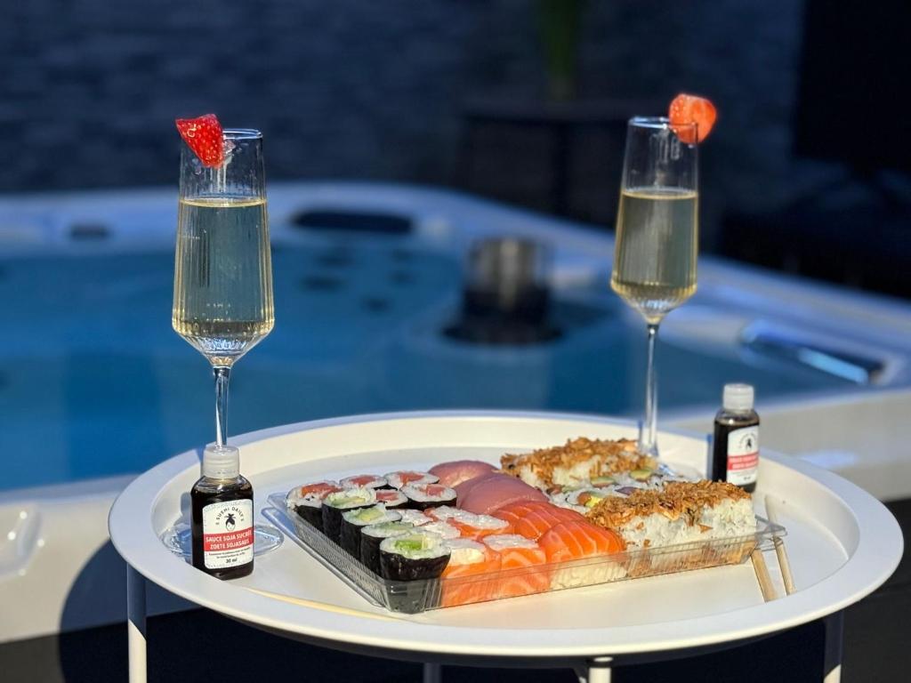 une assiette blanche avec des sushis et deux verres de vin dans l'établissement Suite SPA PRIVÉE, à Portet-sur-Garonne