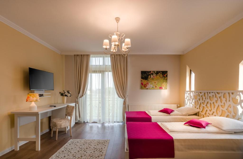 a hotel room with two beds and a desk and a chandelier at Seva Hotel Health Club in Câmpina