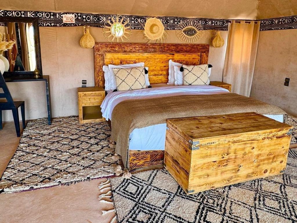 Un dormitorio con una cama grande con cabecero de madera. en Hayati Desert Luxury Camp, en Merzouga