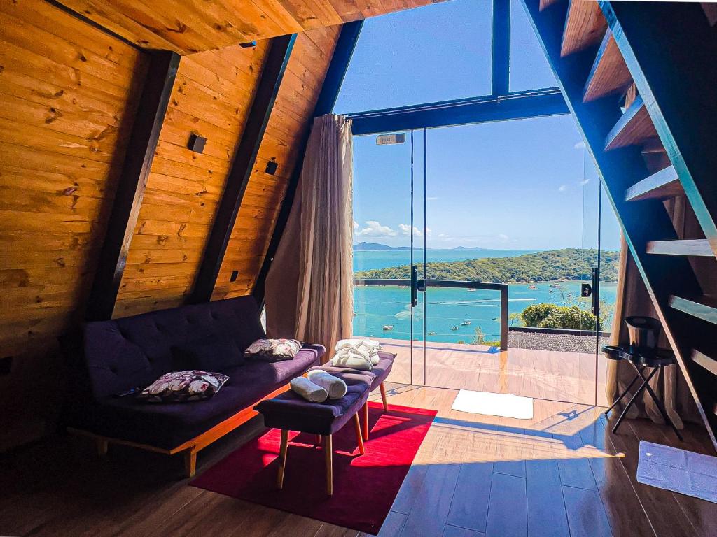 ein Wohnzimmer mit Couch und großem Fenster in der Unterkunft Chales Caixa Daco in Porto Belo