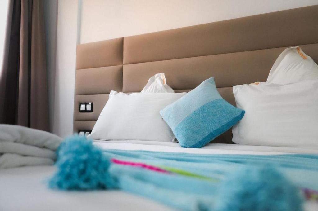 uma cama com almofadas brancas e um cobertor azul em Hôtel Mansour em Dakhla
