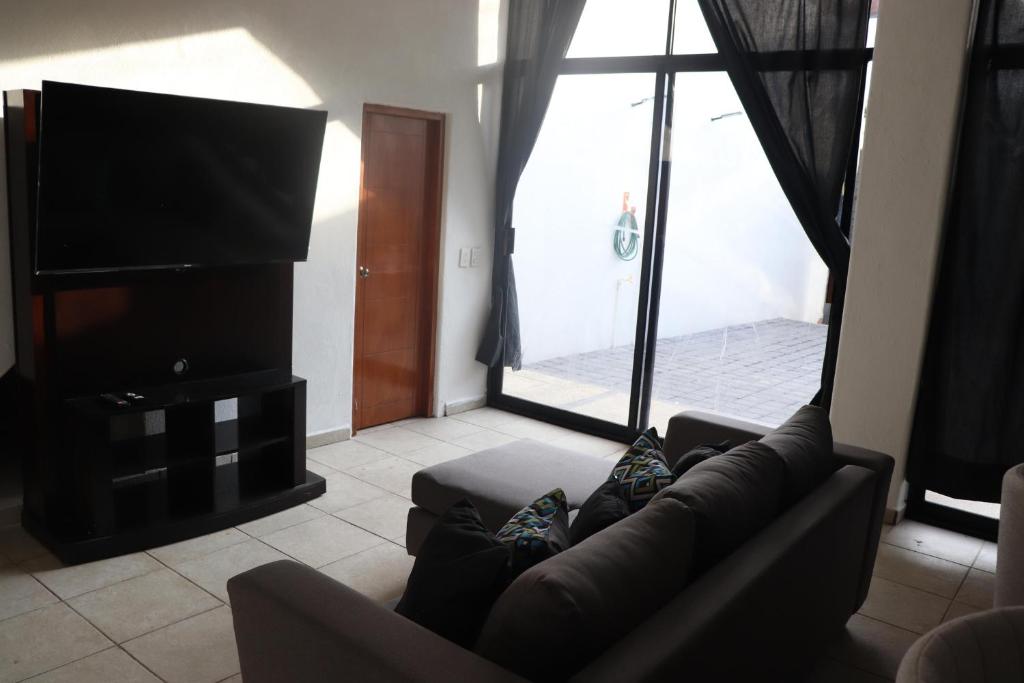 een woonkamer met een bank en een flatscreen-tv bij Habitacion con baño privado La Perla in Acapulco