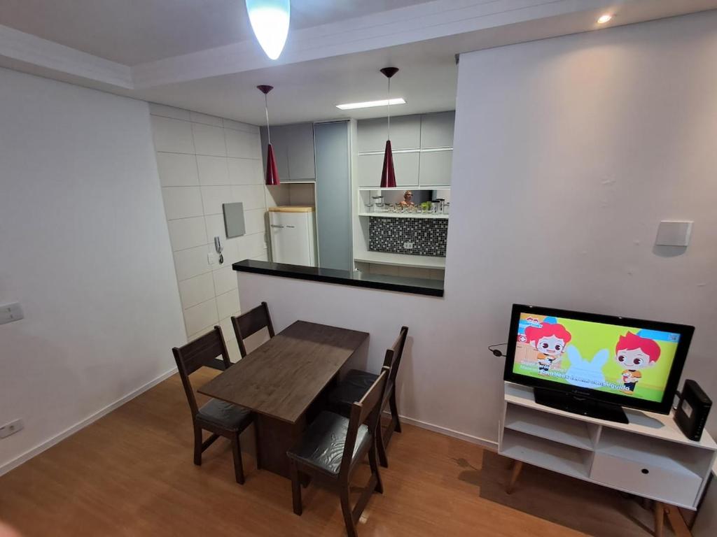 Una cocina y un comedor con una mesa y un televisor. en Family Flat PG - Praia, Musica e Gastronomia, en Praia Grande