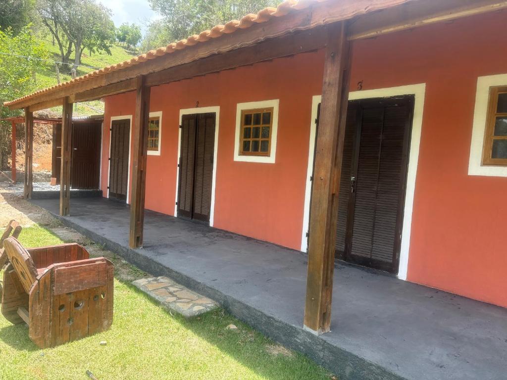 エストレーマにあるSítio do Beto Extrema MGのポーチと外に椅子があるオレンジ色の家
