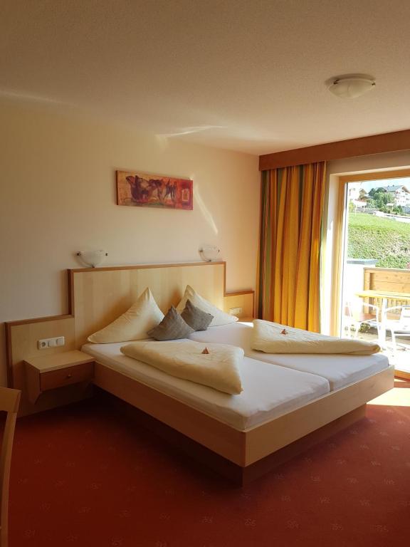 a bedroom with two beds and a large window at Hotel Garni Alpendiamant in Fiss