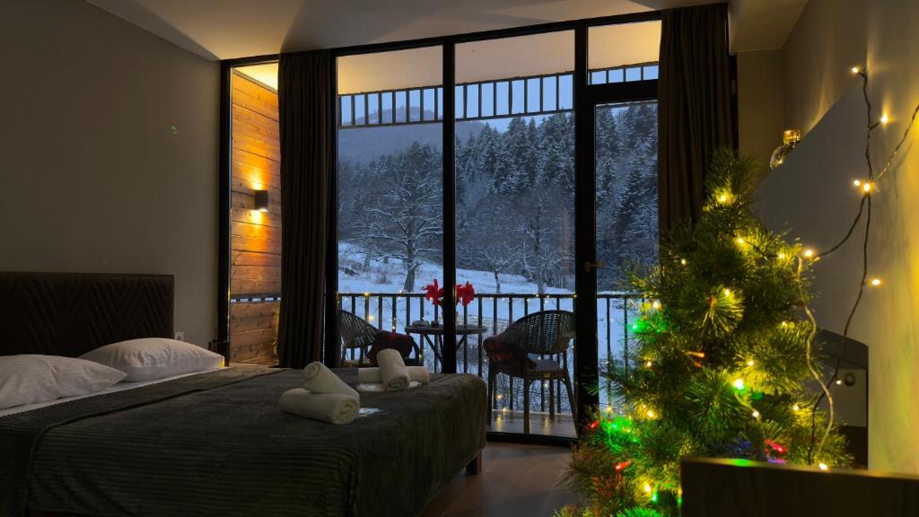 Un dormitorio con un árbol de Navidad y una habitación con ventana. en Didveli Gallery Bakuriani B202 დიდველი გალერეა ბაკურიანი B202, en Bakuriani