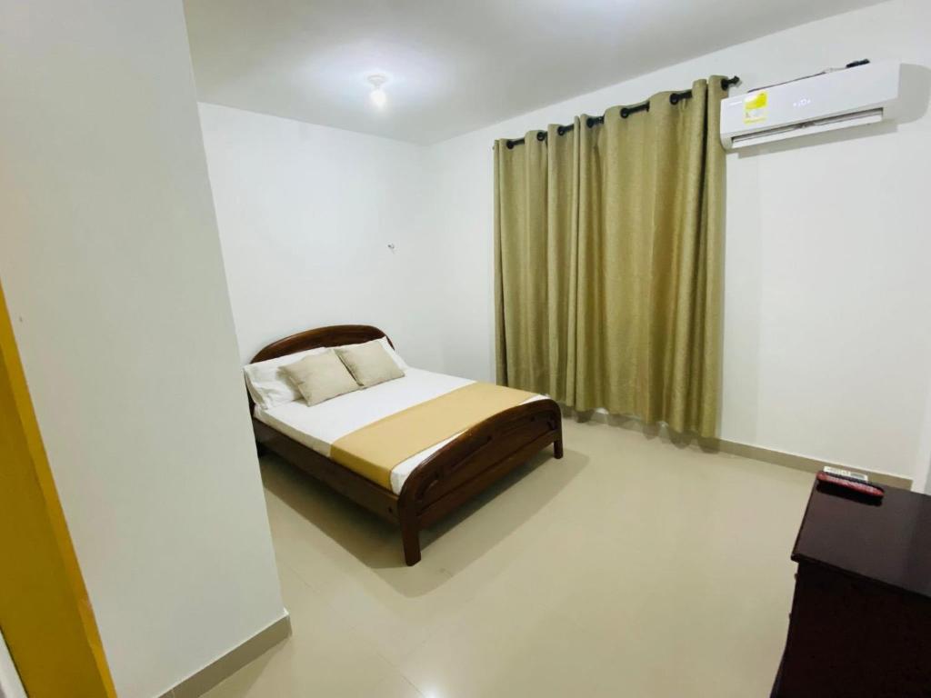 a bedroom with a bed and a green curtain at Hotel Piedra Mágica in Capurganá