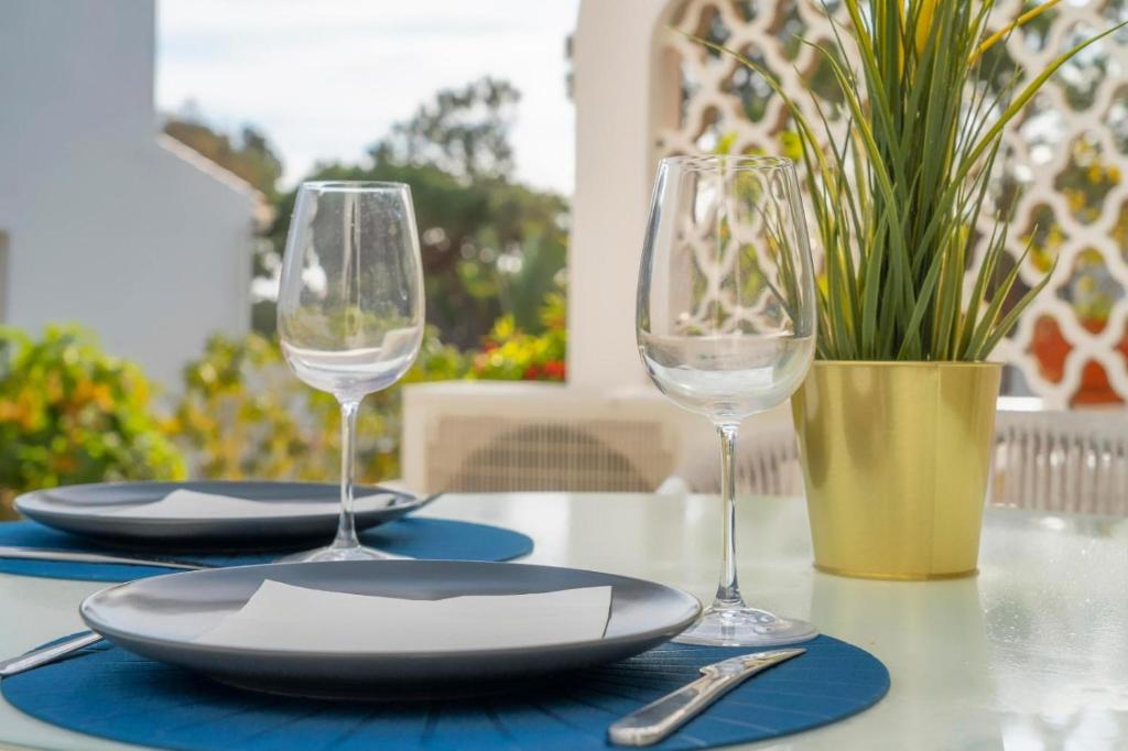 a table with two wine glasses and plates on it at Casa do Gil in Loulé