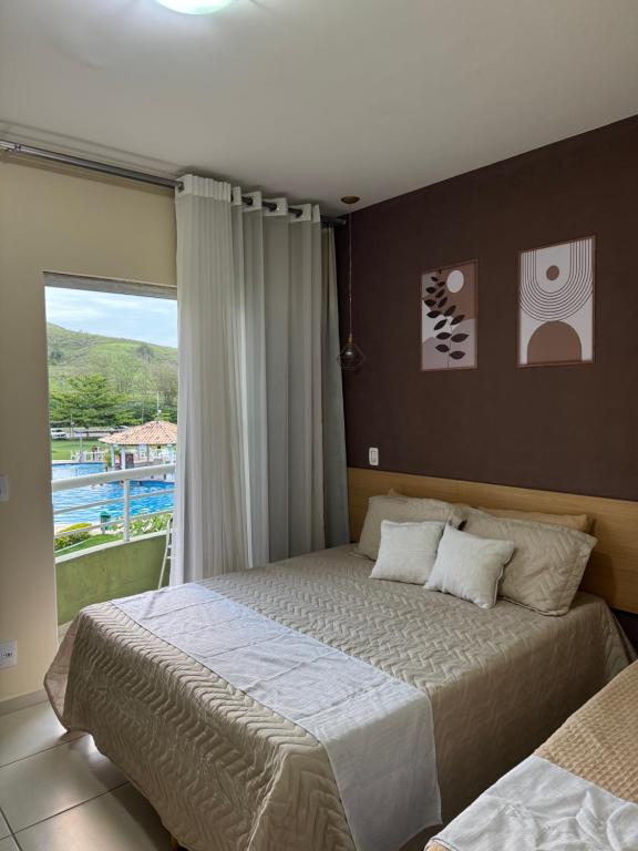 una camera da letto con un letto e una grande finestra di Apartamento Flat 204 Condomínio Village a Barra do Piraí