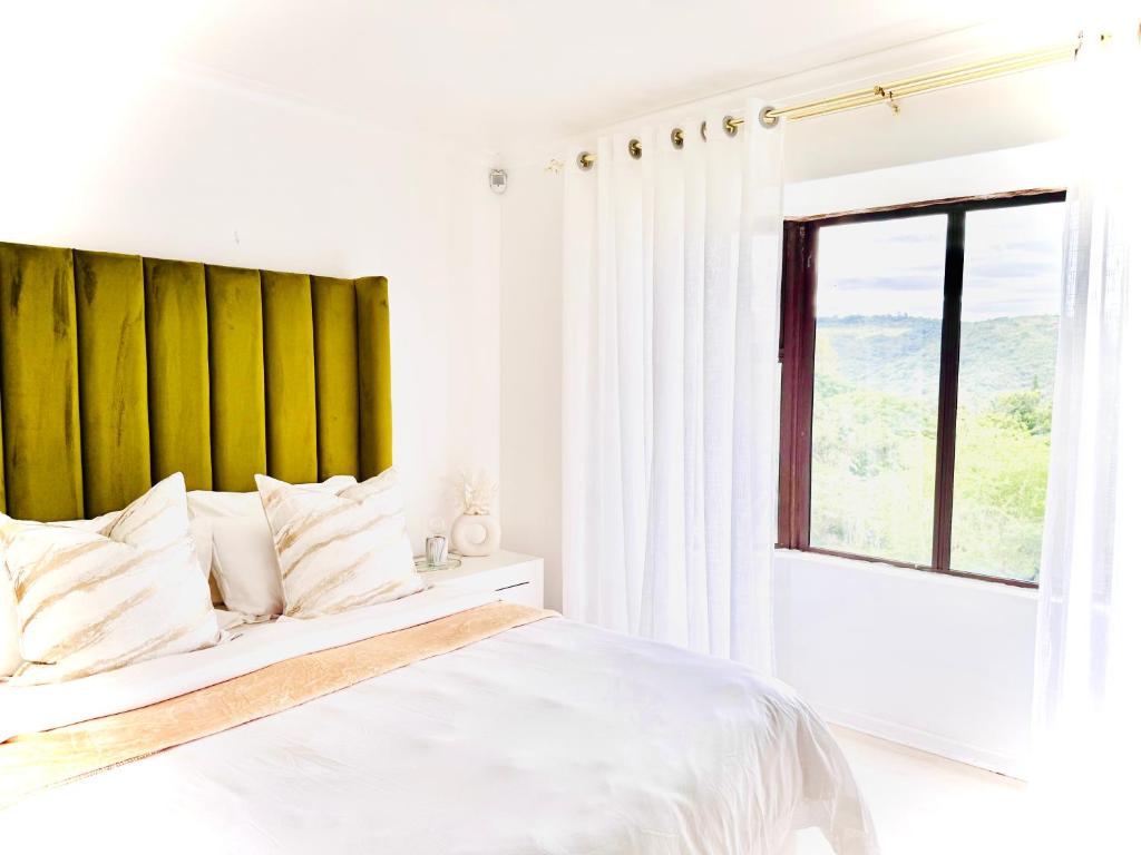 a white bedroom with a large bed and a window at The Cherry Apartment Nahoon Valley in East London