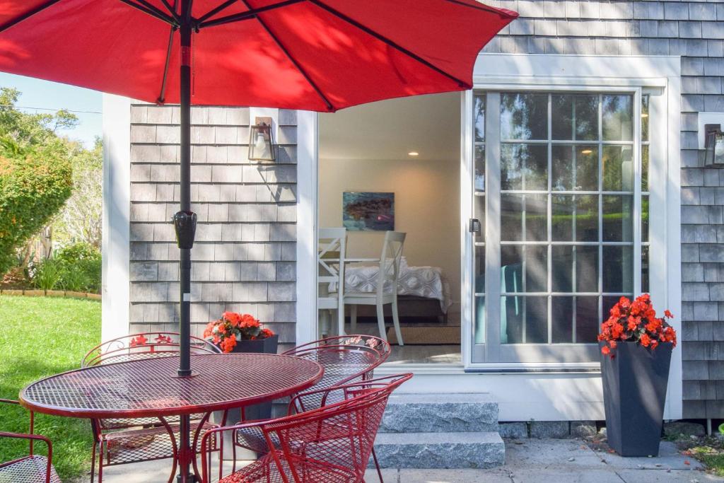 a table and chairs with a red umbrella on a porch at East End Condo w Beach Access in Provincetown