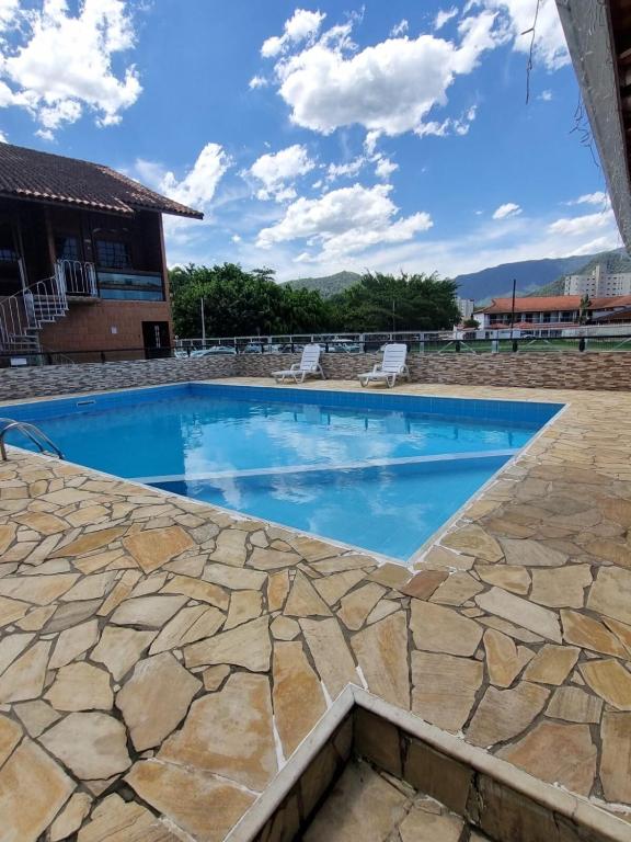 a swimming pool with a stone patio and blue water at Flat I - 50 Metros da Praia in Caraguatatuba