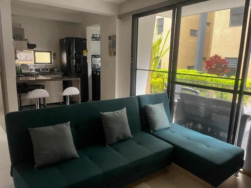 een blauwe bank in een woonkamer met een groot raam bij Modern apartment surrounded by nature in La Tebaida