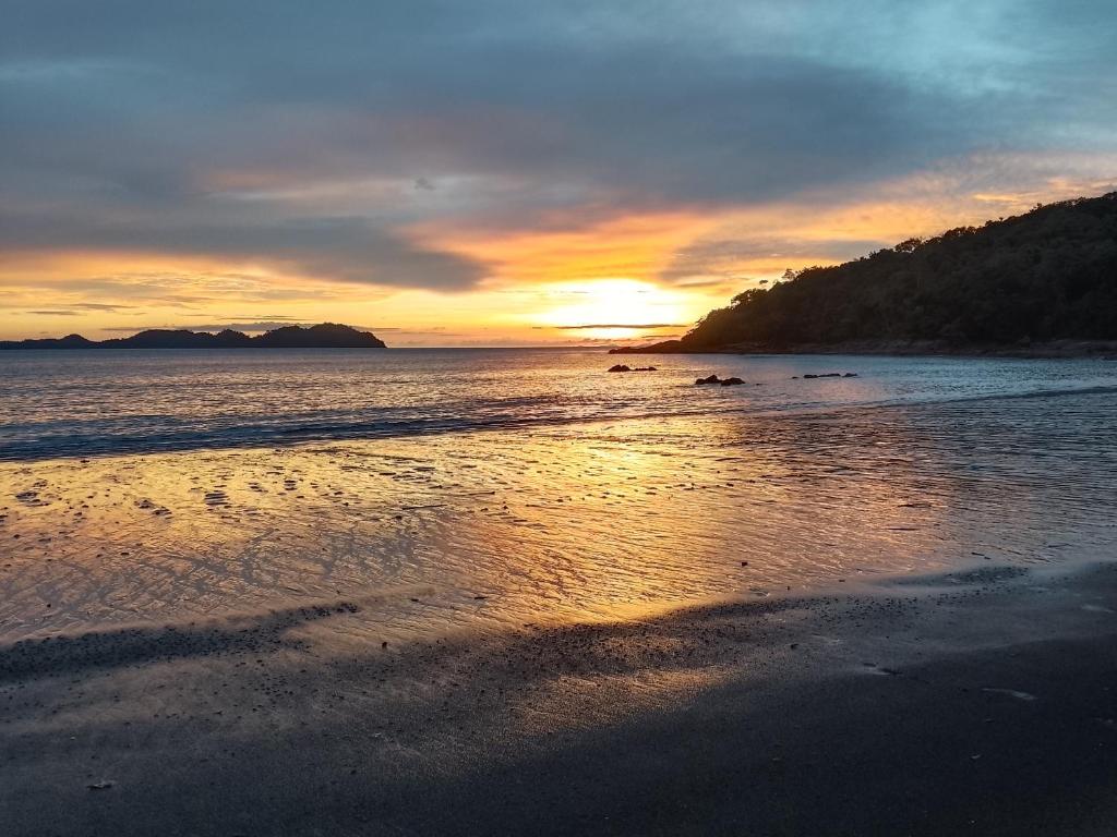 un tramonto su una spiaggia con l'oceano di The Big House บ้านพักริมเล a Ranong