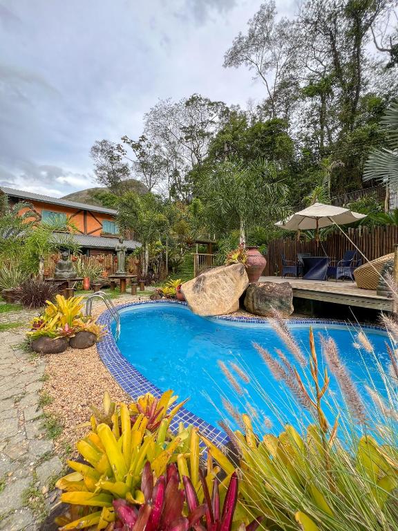 a swimming pool in the middle of a garden at Refúgio Serra das Águas in Araras Petropolis