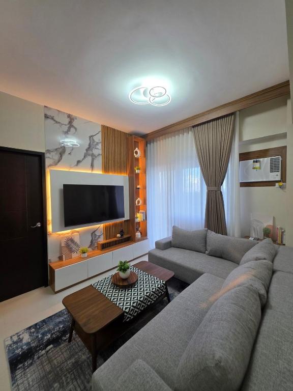 a living room with a couch and a tv at Two Regis Bacolod Cozy 1BR Condo with Balcony in Bacolod
