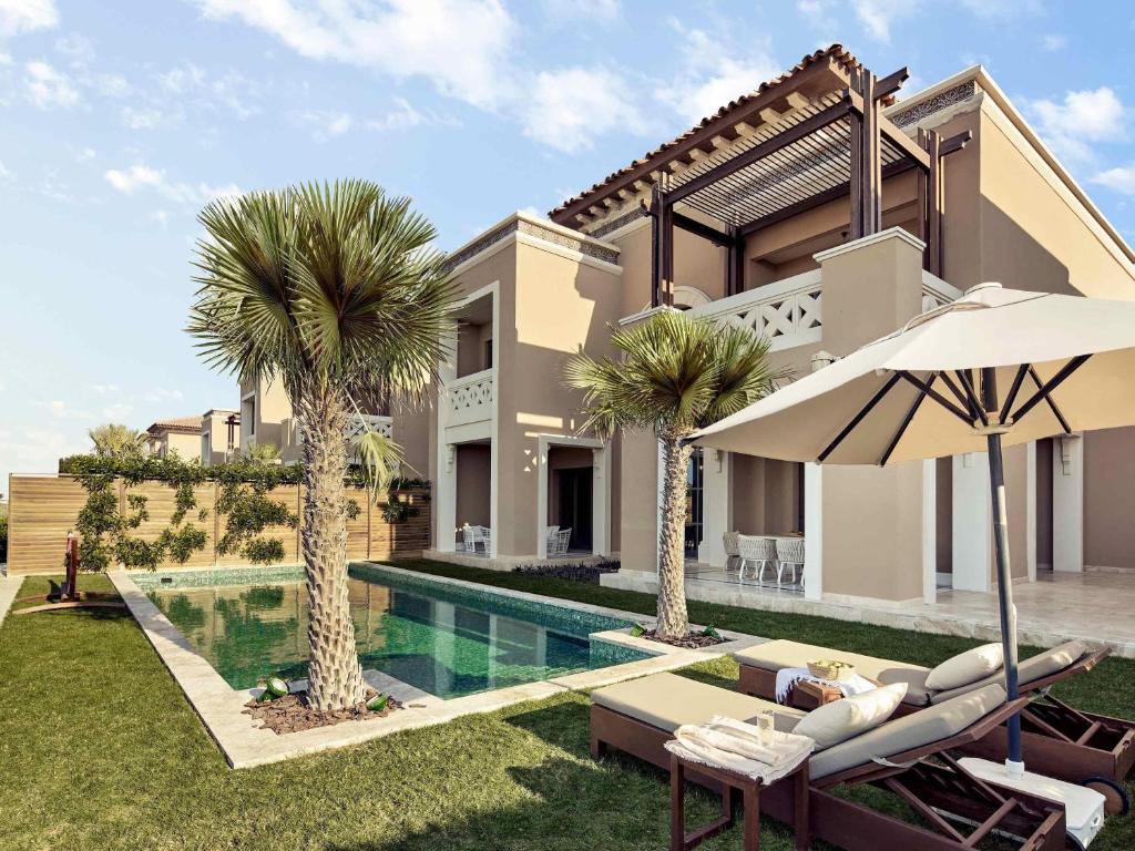 uma villa com piscina e palmeiras em Club Privé By Rixos Saadiyat em Abu Dhabi