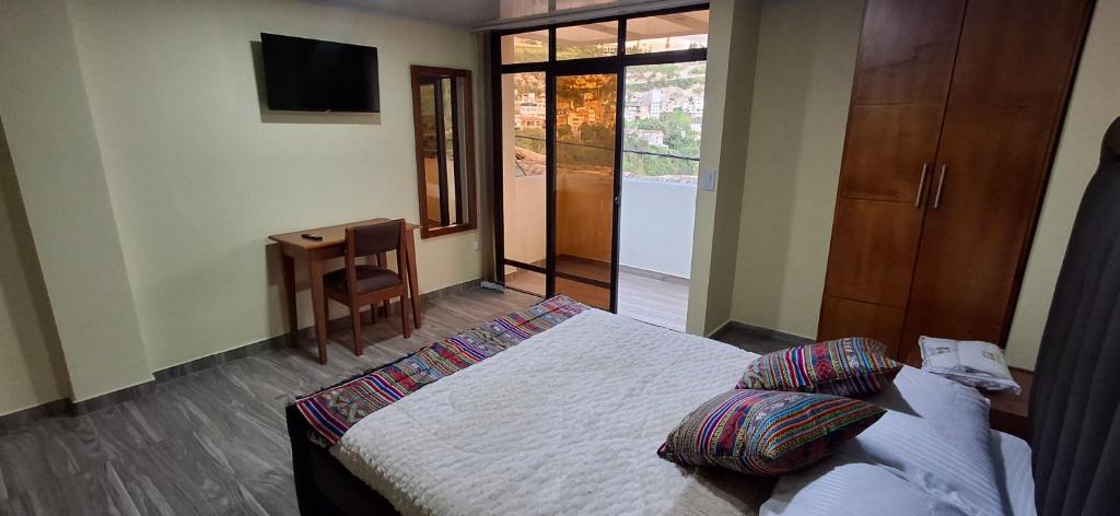 a bedroom with a bed and a desk and a television at Hotel San Marcos Las Lajas in Ipiales