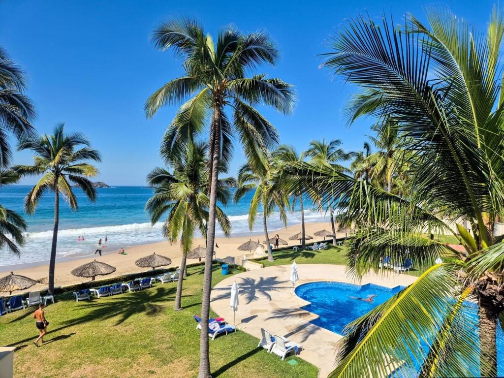 a view of a beach with palm trees and the ocean at Luxury Beachfront Condo at Iguana-Ixtapa in Ixtapa