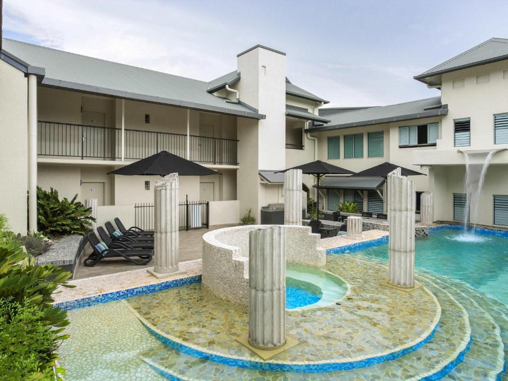 a swimming pool with a fountain in front of a building at Mantra in the Village in Port Douglas