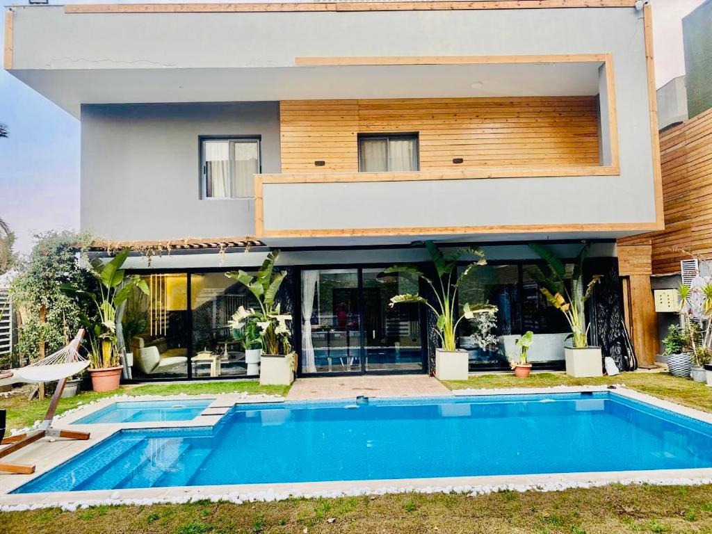 a house with a swimming pool in front of it at Spacious Luxury 5BR Villa with Private Pool near GEM in Kafr Ghaţāţī