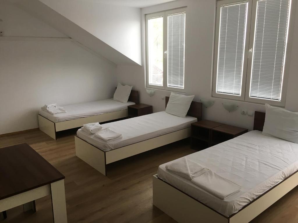 Zimmer mit 3 Betten, einem Tisch und Fenstern in der Unterkunft By The River Hotel in Oryakhovo