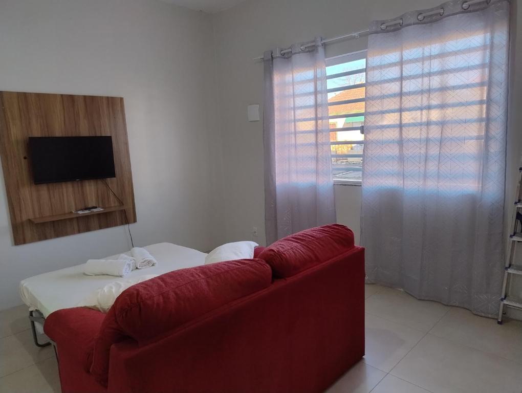 a living room with a red couch and a television at Apartamentos modernos próximos a tudo in São Gabriel