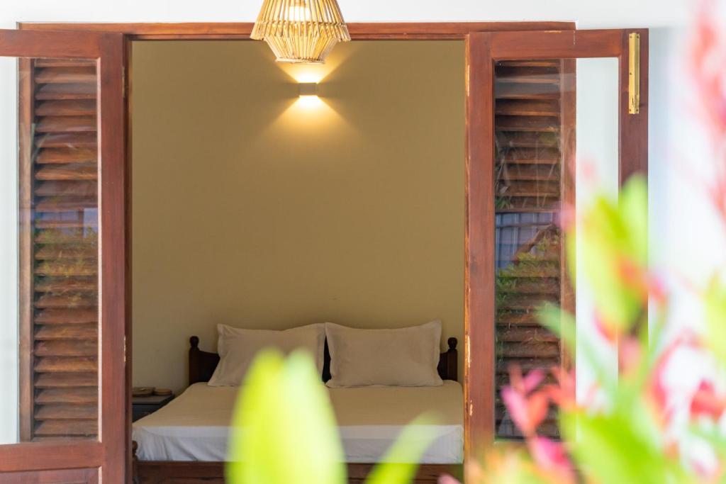 een slaapkamer met een bed en een lamp aan de muur bij Margosa Ahangama in Ahangama