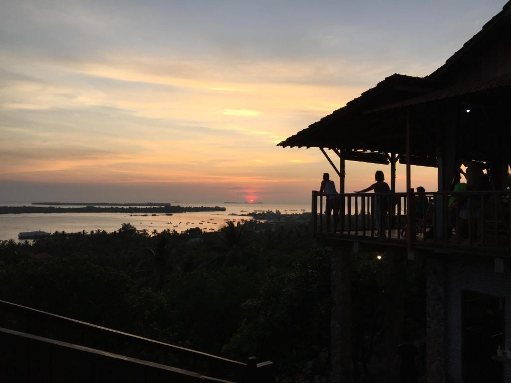 a group of people standing on a balcony watching the sunset at Cocohuts Hotel in Karimunjawa