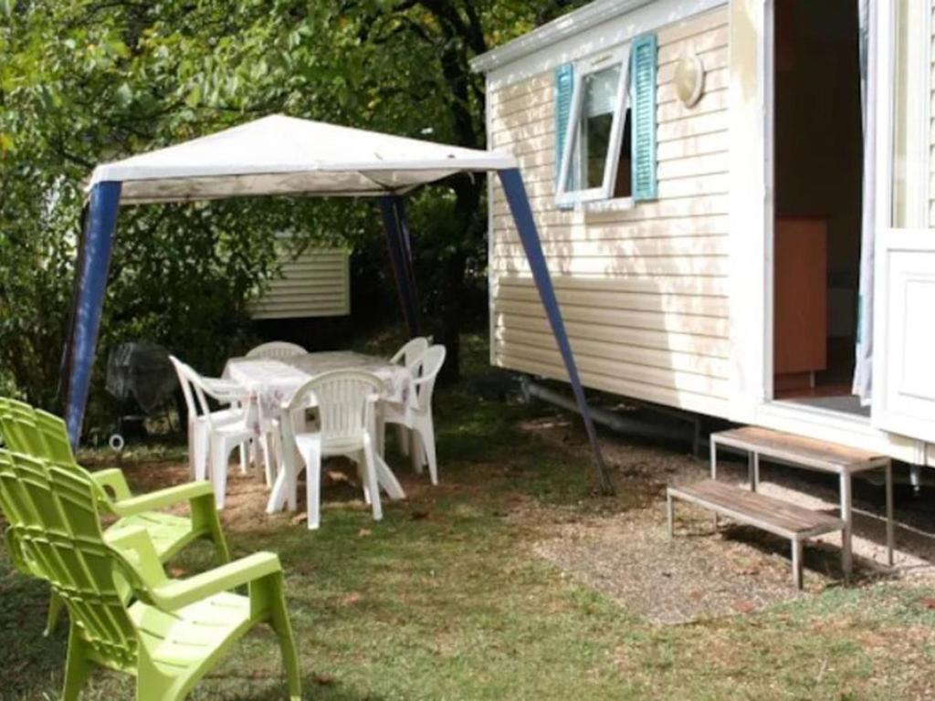 Mobil-home confortable pour 5 pers. en camping à Payrac - API-1-52-1221 في Payrac: مجموعة كراسي وطاولة مع مظلة