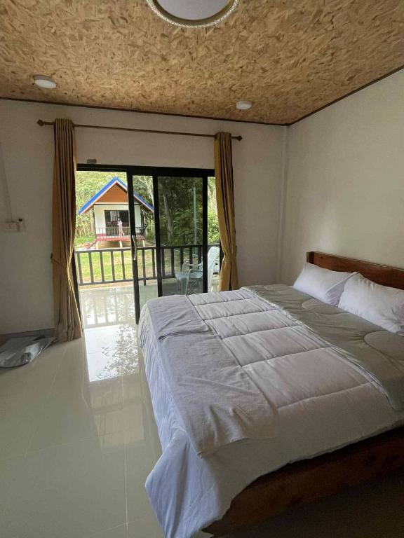 a bedroom with a large bed and a balcony at Grand Bungalow in Ban Ting Rai
