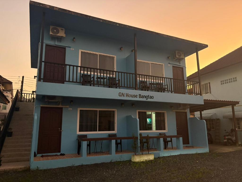 GN House Bangtao في Ban Thalat Choeng Thale: مبنى أزرق مع شرفة وطاولة