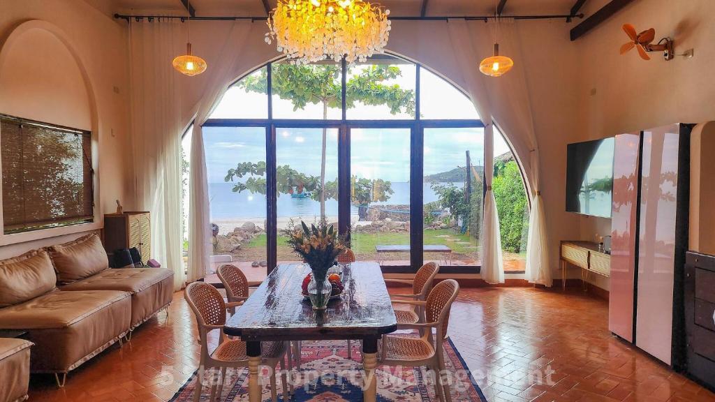 un salon avec une table et une grande fenêtre dans l'établissement Serenity Sands Villa, Beachfront and Mountain View, à Chaloklum