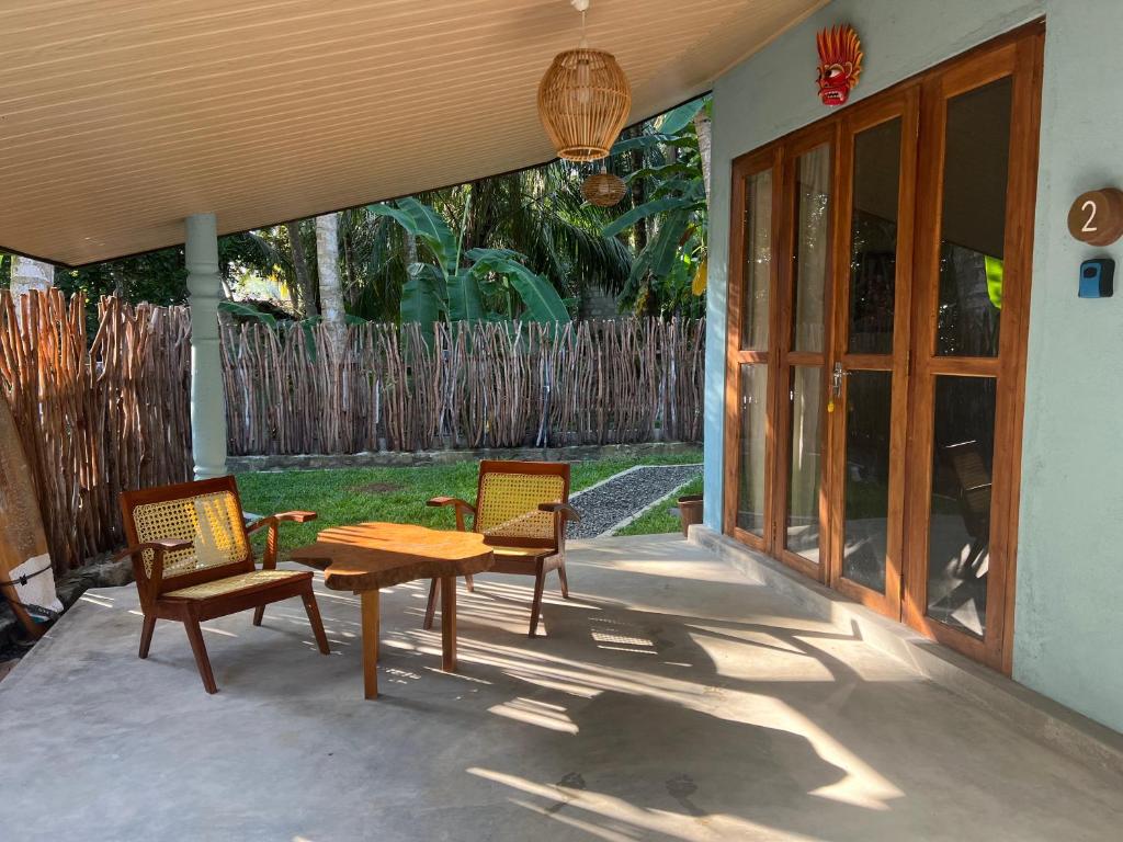 een patio met 2 stoelen en een houten tafel en stoelen bij Into The Blue - Beach House in Unakuruwa