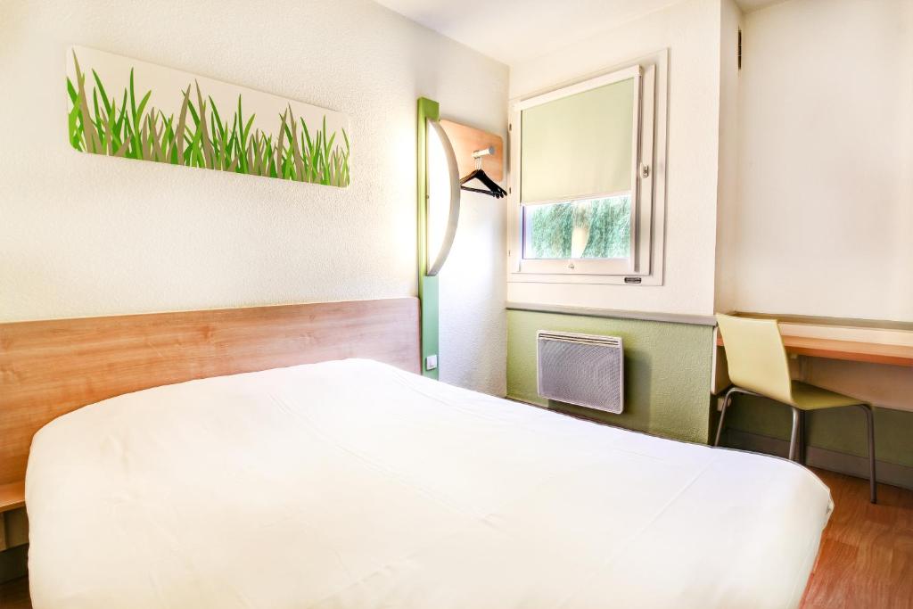 a room with a bed and a desk and a window at ibis budget Chateaudun in Châteaudun