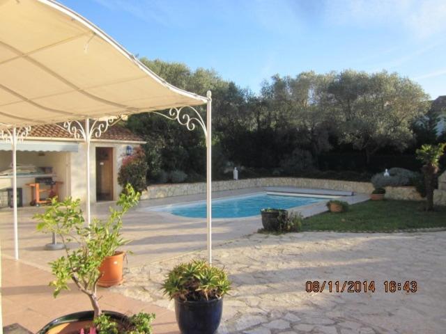 un patio avec un parasol et une piscine dans l'établissement Magnifique villa au calme clim parking piscine, à Six-Fours-les-Plages