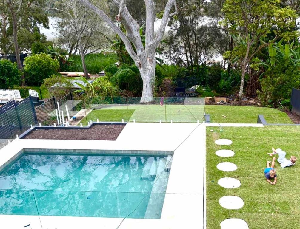a swimming pool in a yard with two people playing at Surf Lodge Avoca Beach Waterfront to Avoca Lake in Avoca Beach