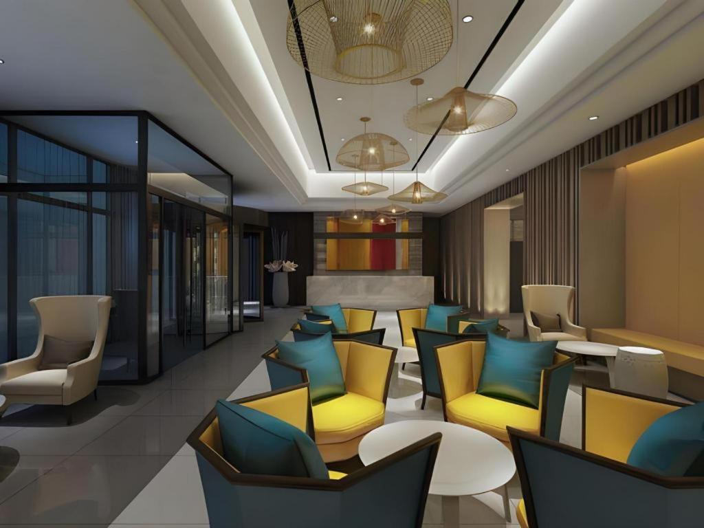 um átrio com mesas e cadeiras amarelas e azuis em Jinjiang Inn Select Xixian New Distict Century Avenue em Xianyang