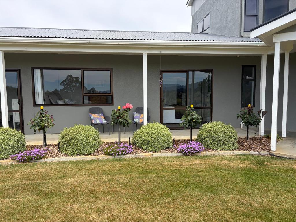 a house with bushes and flowers in front of it at Just Dean Motueka in Lower Moutere
