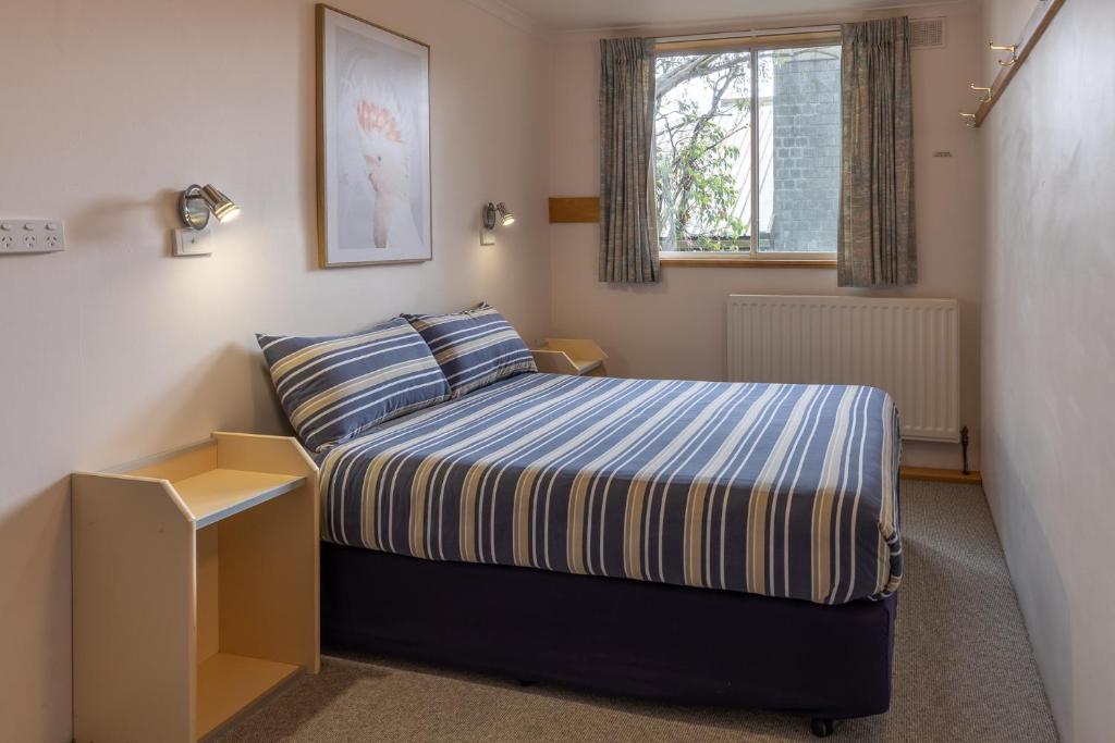 a small bedroom with a bed and a window at Schuss Alpine Club, Falls Creek in Falls Creek