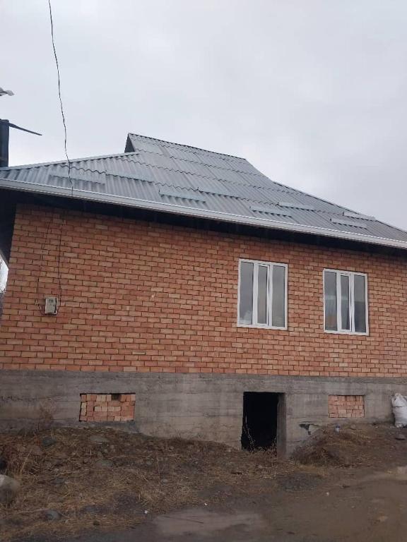 a red brick building with a black roof at Nurdin Guest House in Kashkaldak