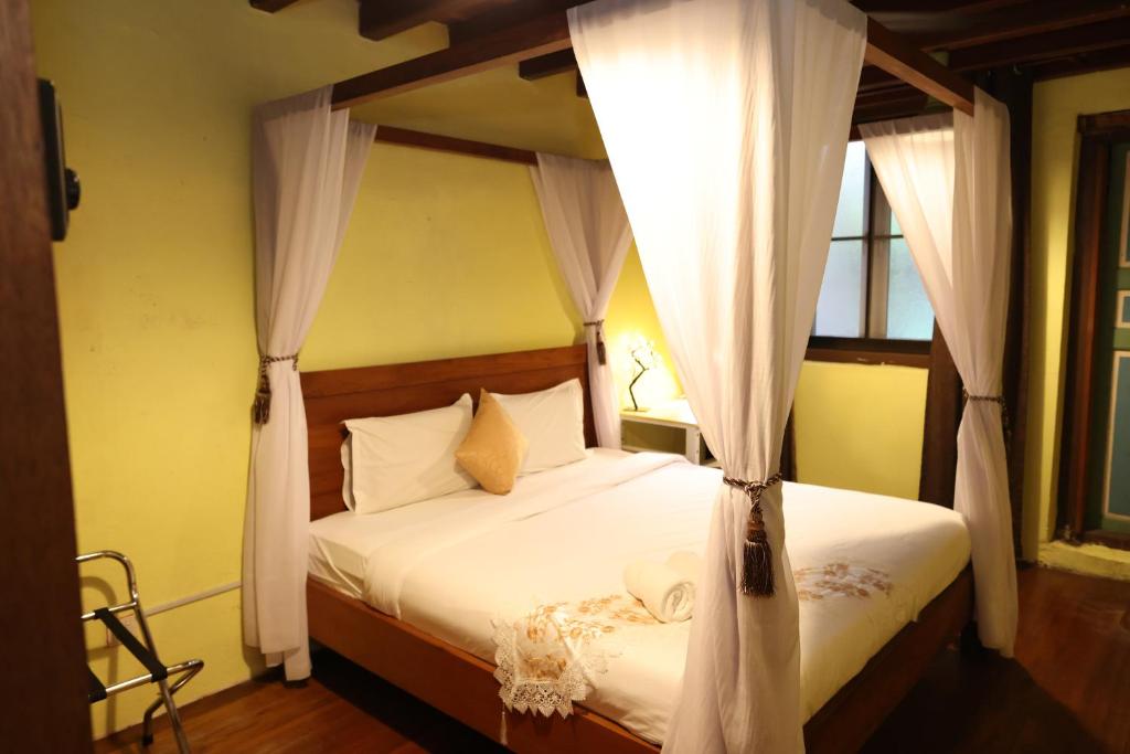Un dormitorio con una cama con dosel y cortinas blancas. en The Lang Hoose, en George Town