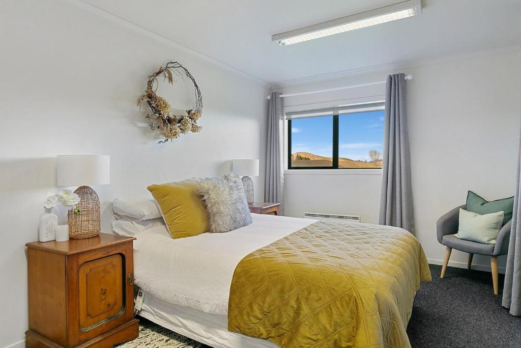 Un dormitorio con una cama y una silla y una ventana. en The Stables Lake and Country Retreat, en Taupo