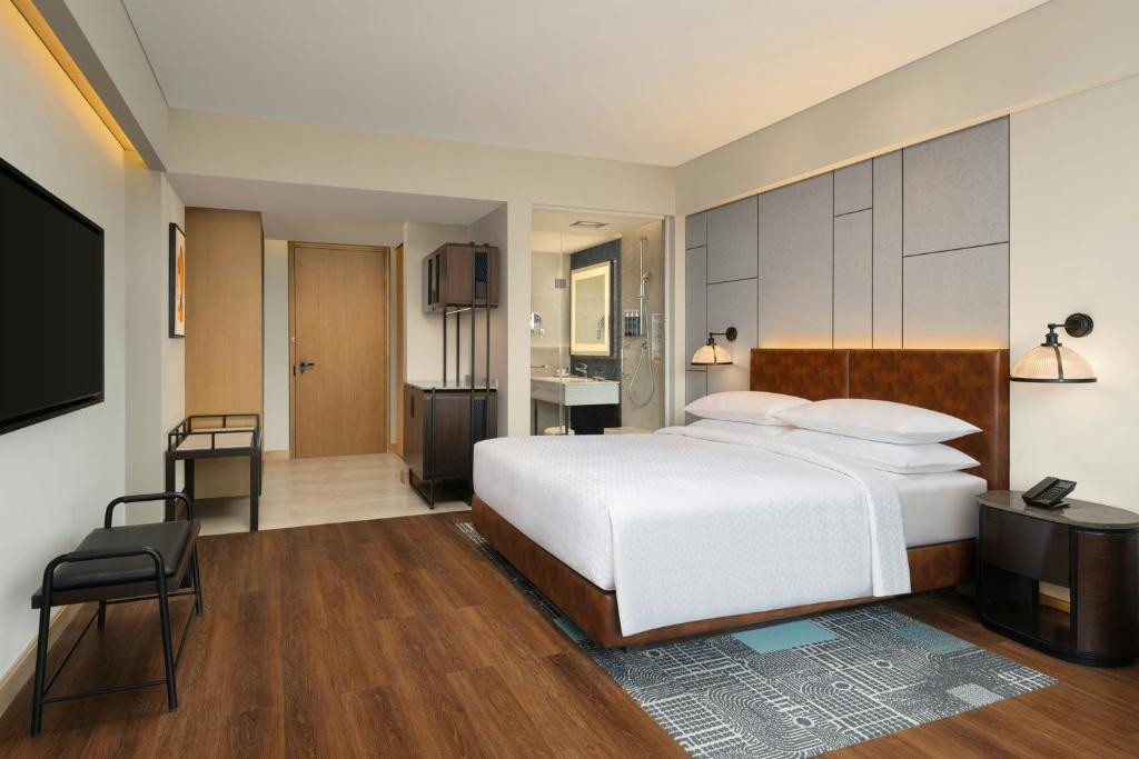 een slaapkamer met een groot wit bed en een televisie bij Four Points by Sheraton Amritsar, Mall Road in Amritsar