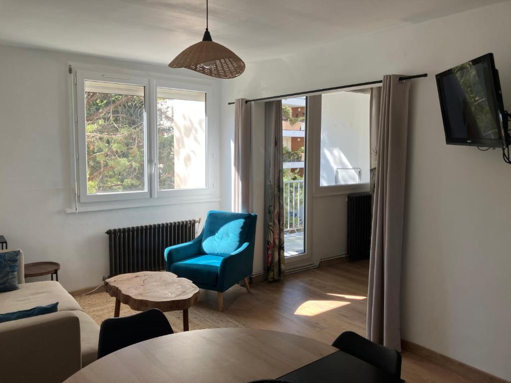 un salon avec une chaise bleue et une table dans l'établissement grand appartement Sete, à Sète